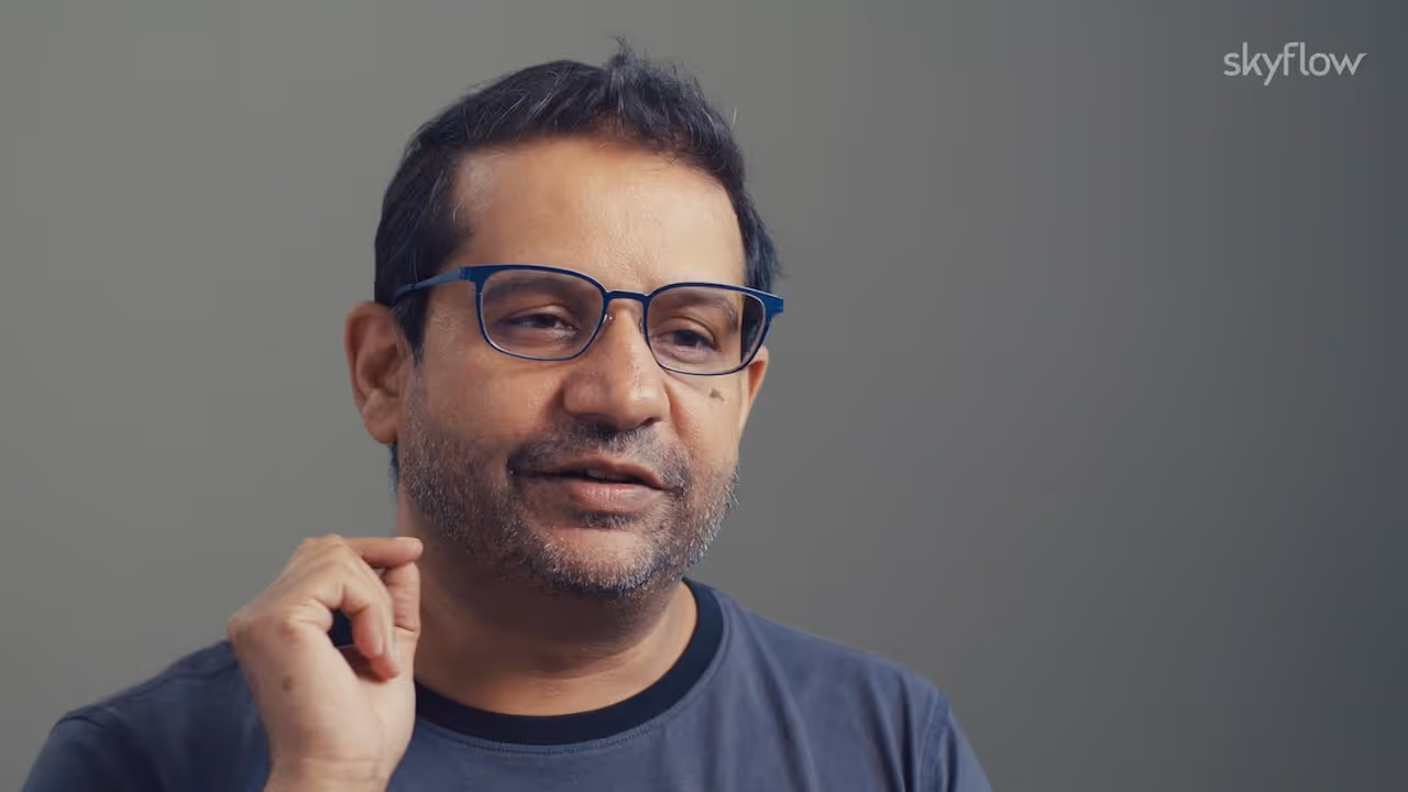Man with glasses and a short beard speaking against a plain gray background with skyflow logo.